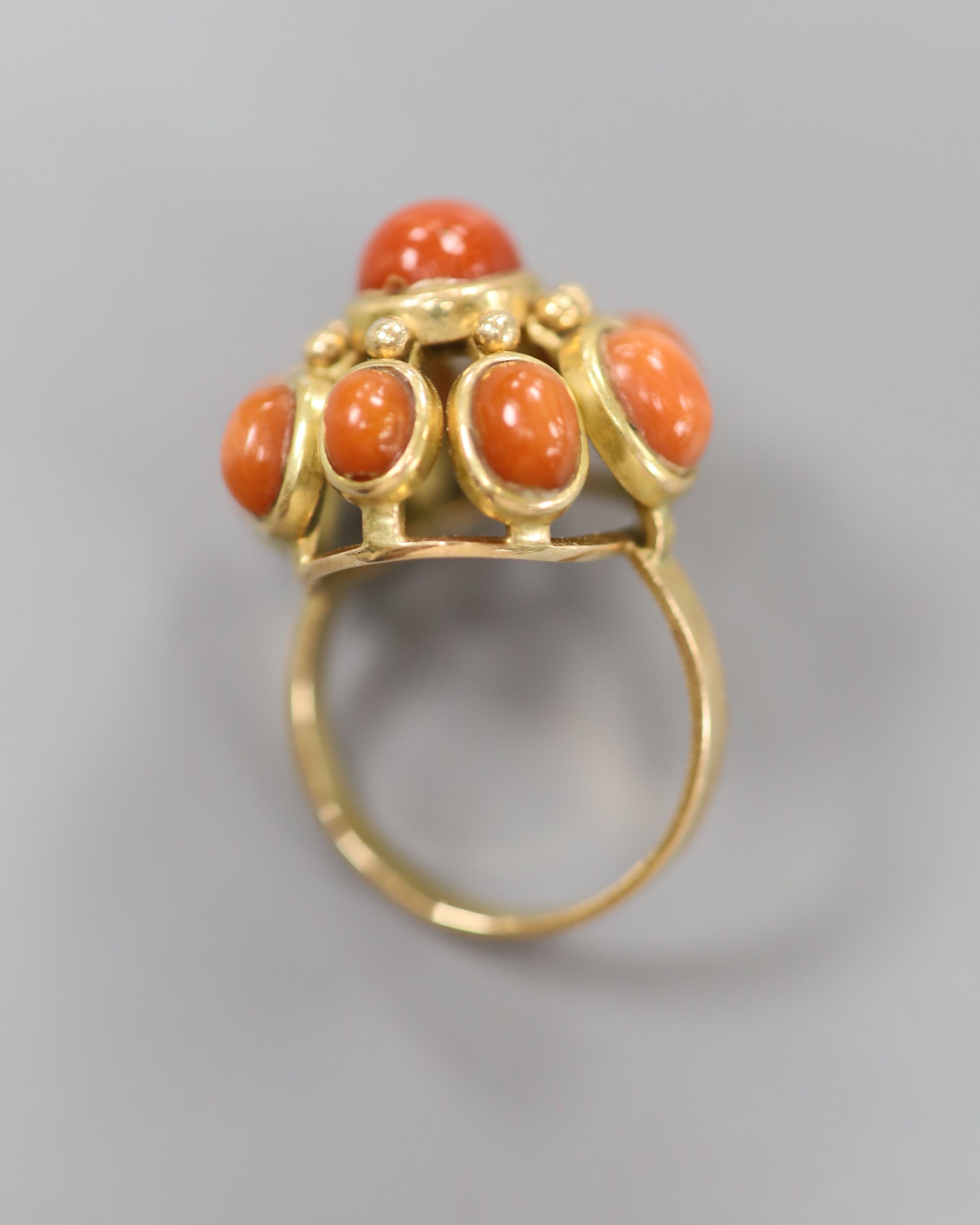 A yellow metal and nine stone coral bead cluster set dress ring, size O, gross 9.1 grams.